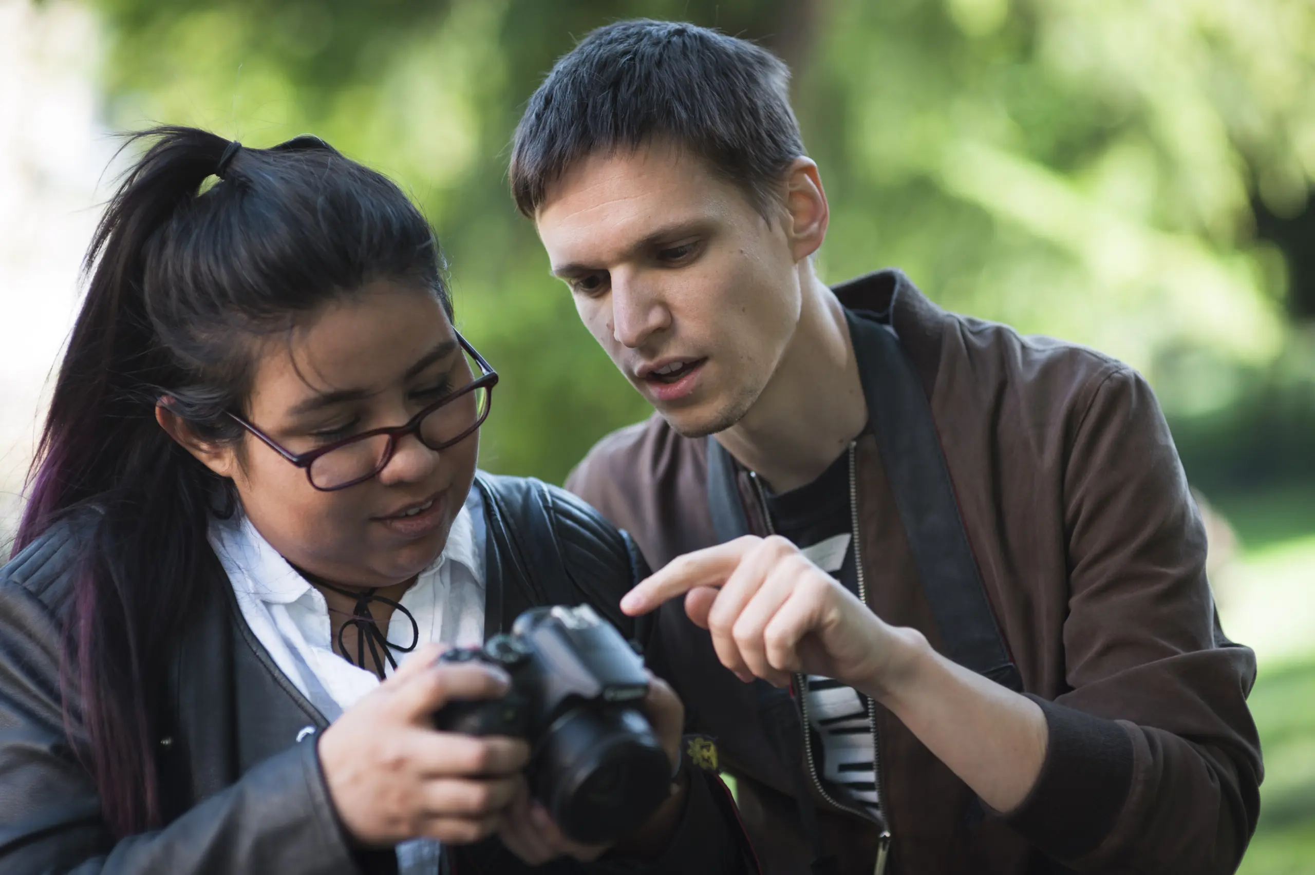 a man and a woman looking at the settings on a camera
